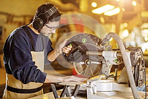 Carpenter work with mitre saw in factory