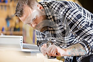 Carpenter work with plane on wood plank in workshop