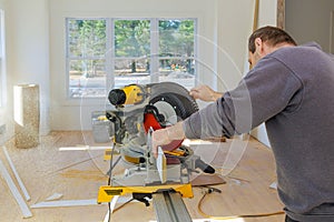 Carpenter at work using circular saw cutting wood moldings baseboard