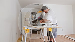 Carpenter at work using circular saw cutting wood moldings baseboard