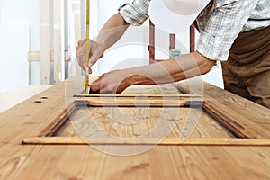 Carpenter work the wood, measuring a thickness with angle square photo