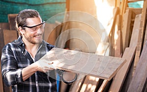 Carpenter work in wood workshop selecting timber for his woddwork