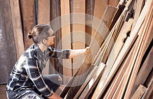 Carpenter work in wood workshop selecting timber for his woddwork