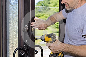 Carpenter worker installing the lock on the entrance door of the new home