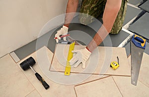 Carpenter worker installing wood parquet board during flooring w