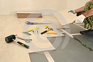 Carpenter worker installing wood parquet board during flooring w