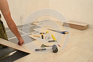 Carpenter worker installing wood parquet board during flooring w