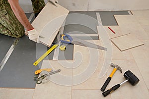 Carpenter worker installing wood parquet board during flooring w