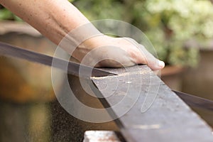 Carpenter worker sawing wood board with hand saw