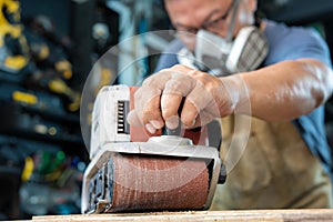 Carpenter working with belt sander polishing on wooden in workshop ,DIY maker and woodworking concept. selective focus