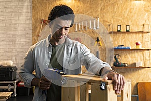 Carpenter working with drill in workshop