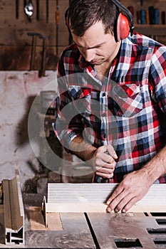 Carpenter working on an electric buzz saw cutting some boards