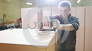 Carpenter working with an electric industrial stapler on the factory, fixing furniture details, close-up