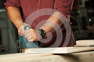 Carpenter working with electric planer.