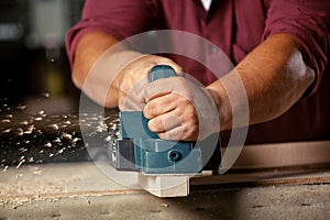 Carpenter working with electric planer.