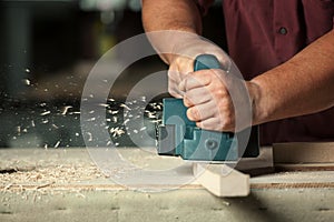 Carpenter working with electric planer.