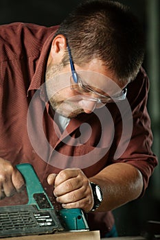 Carpenter working with electric planer.