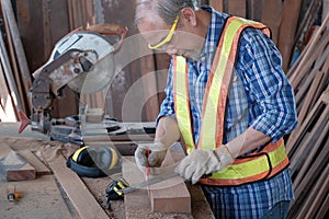 Carpenter working hand to measure lumber with metal ruler & pencil to marking in woodworking factory. There is many craft