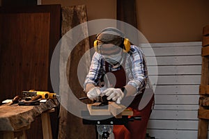 Carpenter working hard while planing on wood with a manual wood planer or plane tool in wood workshop or carpentry workplace,