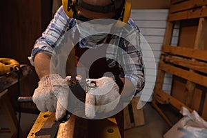 Carpenter working hard while planing on wood with a manual wood planer or plane tool in workshop or carpentry workplace, Craftsman