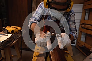 Carpenter working hard while planing on wood with a manual wood planer or plane tool in workshop or carpentry workplace, Craftsman