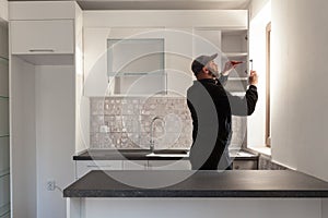 Carpenter working on new kitchen. Handyman fixing a door in a kitchen