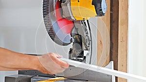 Carpenter working using circular saw rotating saw cutting wood baseboard