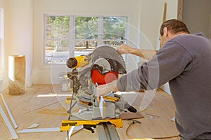Carpenter working using circular saw rotating saw cutting wood baseboard