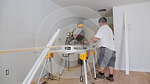 Carpenter working using circular saw rotating saw cutting wood baseboard