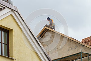 A carpenter is working on a wooden roof structure at a construction site. Industrial roofing system with wooden beams, beams and