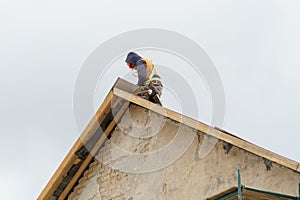 A carpenter is working on a wooden roof structure at a construction site. Industrial roofing system with wooden beams, beams and