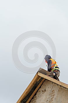 A carpenter is working on a wooden roof structure at a construction site. Industrial roofing system with wooden beams, beams and