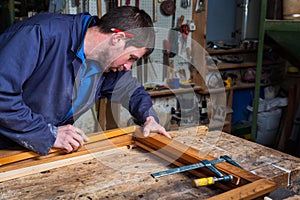 Carpenter working on a Wooden Window Frame in his Workshop