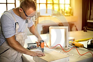 Carpenter working on woodworking machines in carpentry shop