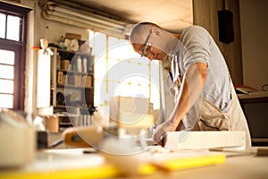 Carpenter working on woodworking machines in carpentry shop