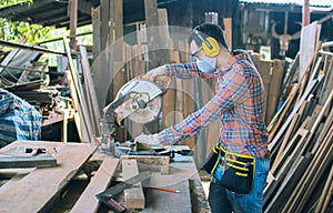 A carpenter is working in a woodworking office.caucasion white male carpenter using electric circular saw cut wood