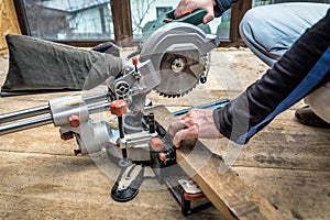 Carpenter works with a circular saw miter saw in a workshop