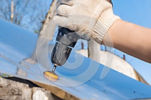 The carpenter works with an electric drill.