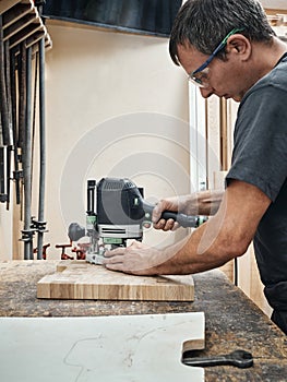 A carpenter works with a hand-held grinding machine