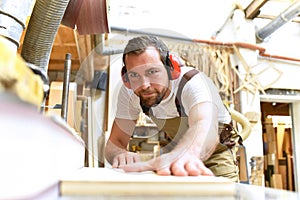 carpenter works in a joinery - workshop for woodworking and sawing