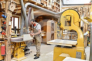 carpenter works in a joinery - workshop for woodworking and sawing