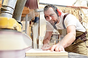 carpenter works in a joinery - workshop for woodworking and sawing
