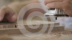 Carpenter works with a manual electric milling cutter. woodworker processes a wooden board