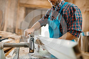 Carpenter works on plane machine, woodworking