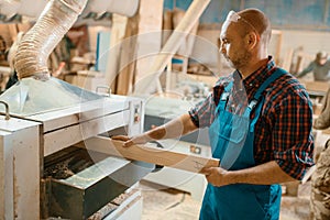 Carpenter works on plane machine, woodworking