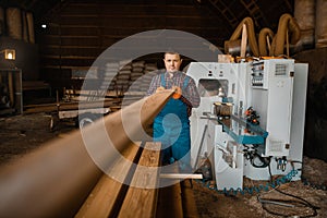 Carpenter works on woodworking machine, lumber