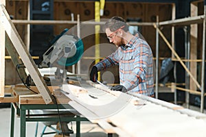 A carpenter works on woodworking the machine tool. Man collects furniture boxes. Saws furniture details with a circular