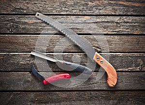 A carpenter& x27;s working tool on a wooden table. Saw, dimes, knife, top view.