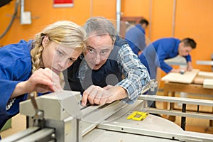 carpenter and young female apprentice working together in workshop