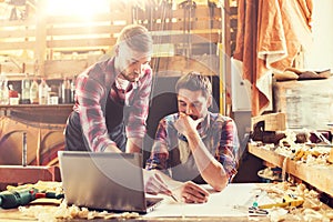 Carpenters with laptop and blueprint at workshop